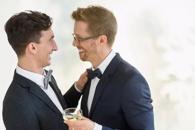 Caucasian gay grooms hugging at wedding