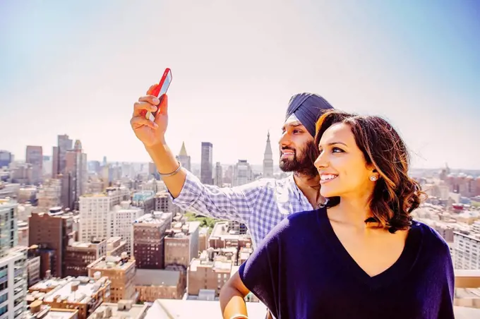Indian couple taking selfie over New York cityscape, New York, United States