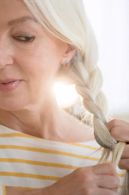 Caucasian woman braiding her hair