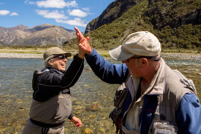 Caucasian couple high-fiving in remote river