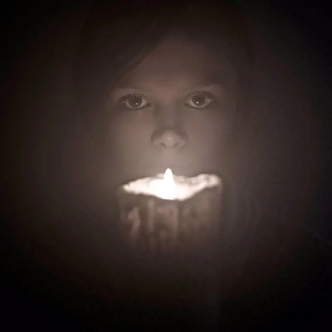 Caucasian woman holding candle near face
