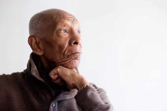 Older Black man resting chin in hand