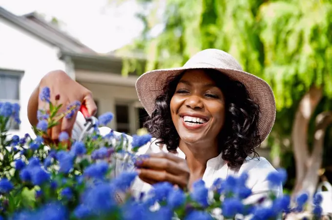 Smiling woman pruning flowers in garden