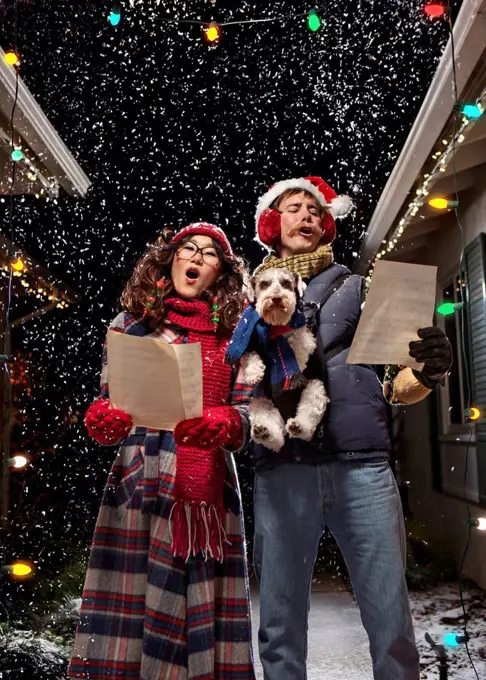 Couple singing Christmas carols with dog