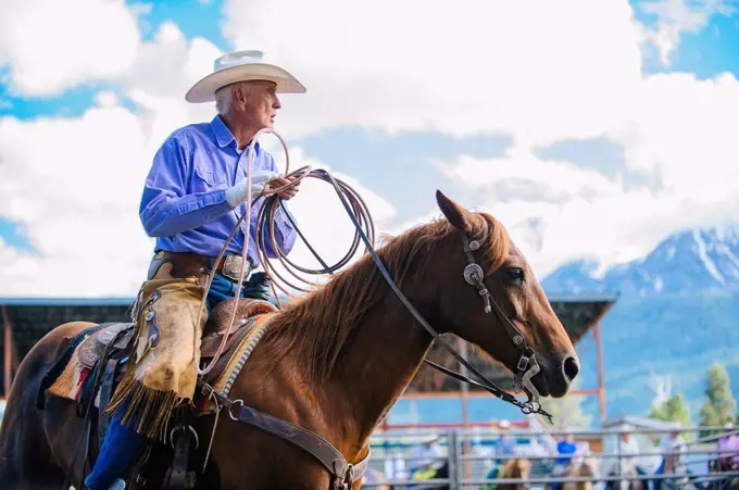 Older Caucasian cowboy riding horse at rodeo
