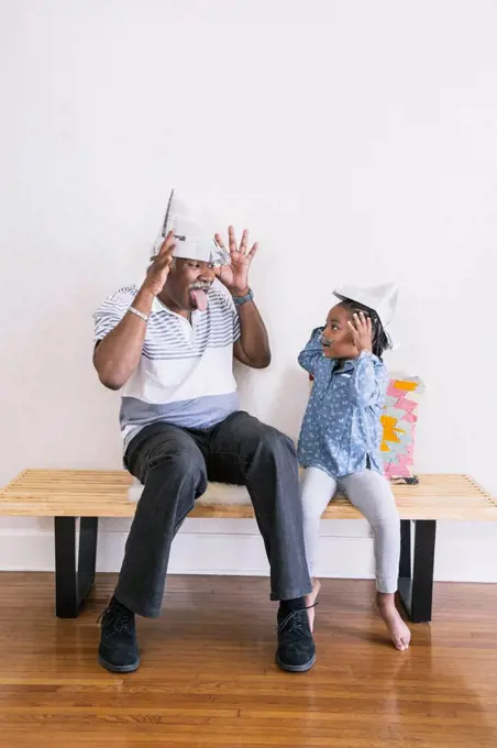 African American grandfather and granddaughter playing on bench