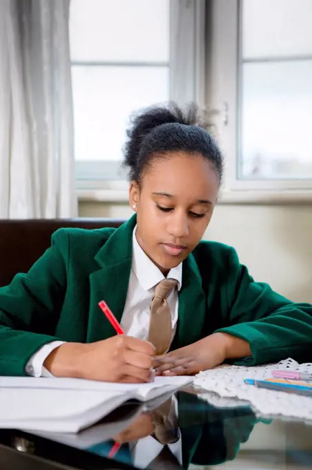 Black girl wearing school uniform doing homework