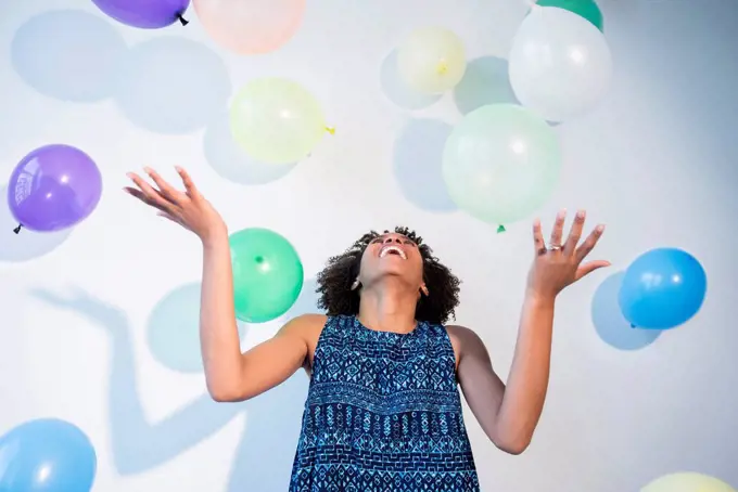 Black woman watching falling balloons