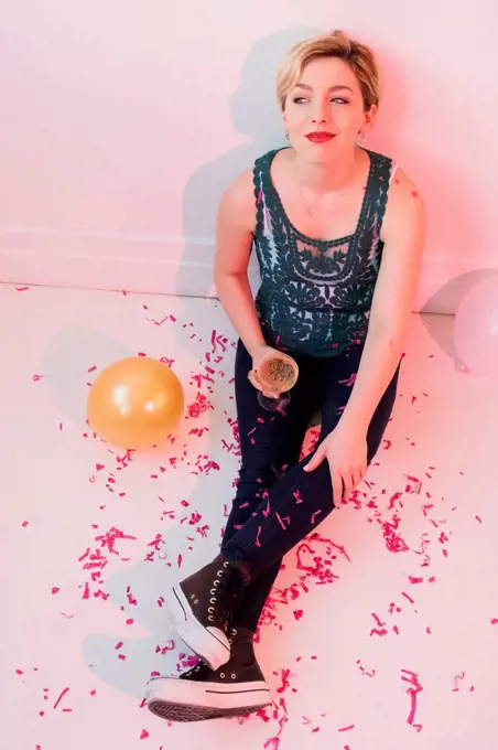 Caucasian woman sitting on floor at party covered in confetti