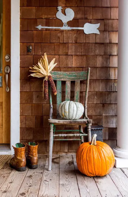 Pumpkins and corn on porch with boots in autumn