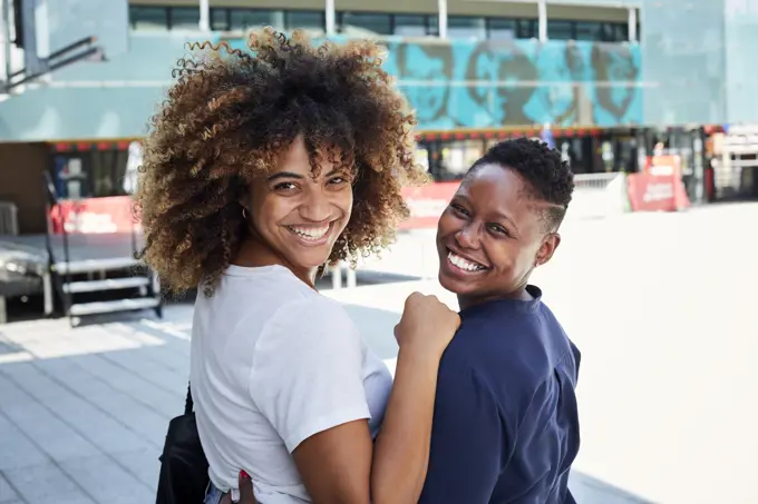 Portrait of smiling Black women hugging in city