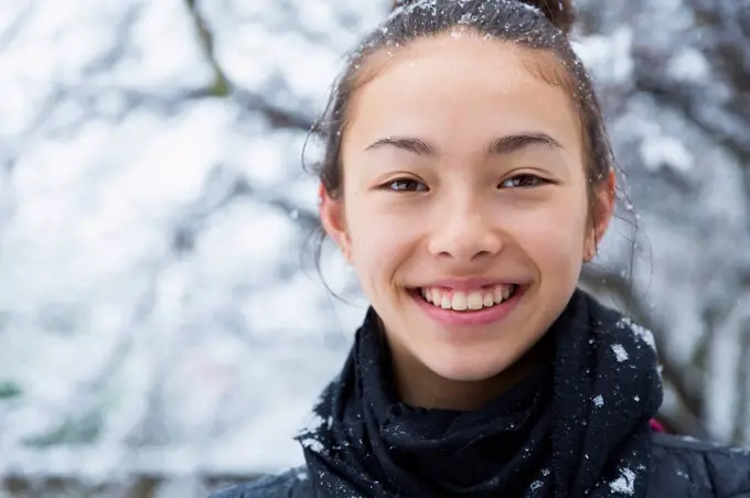 Smiling Mixed Race girl covered in snow