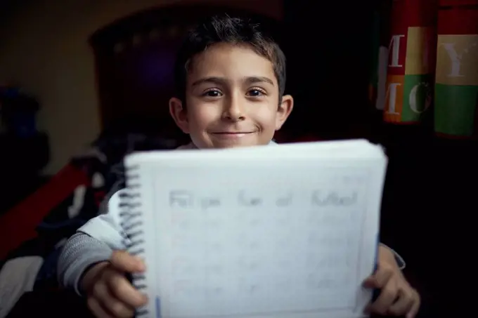 Proud Hispanic boy practicing writing alphabet
