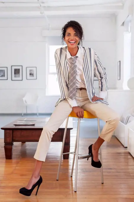 Smiling Mixed Race businesswoman sitting on stool