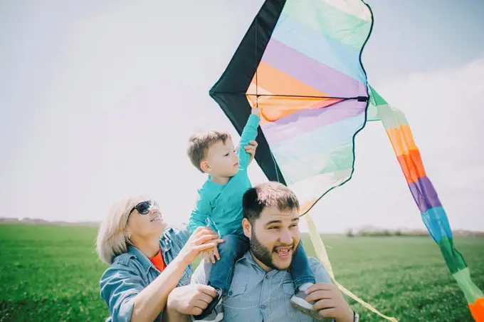Caucasian boy flying kite with father and grandmother