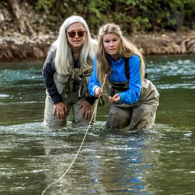 Caucasian mother and daughter fly fishing
