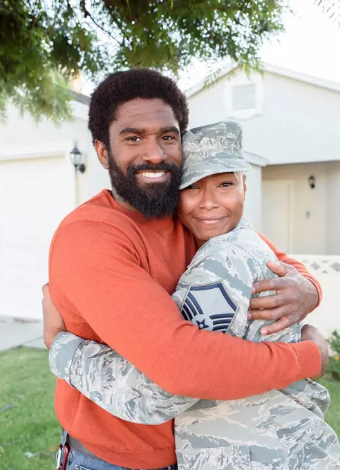 Portrait of black woman soldier hugging man