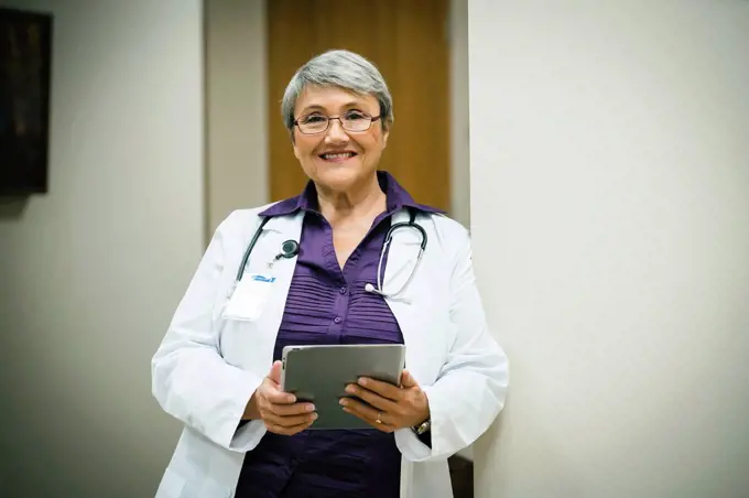 Portrait of smiling mixed race doctor using digital tablet