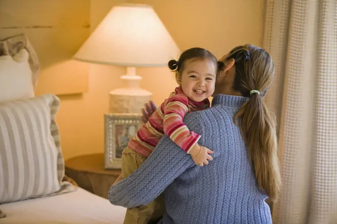 Hispanic mother and daughter hugging in bedroom