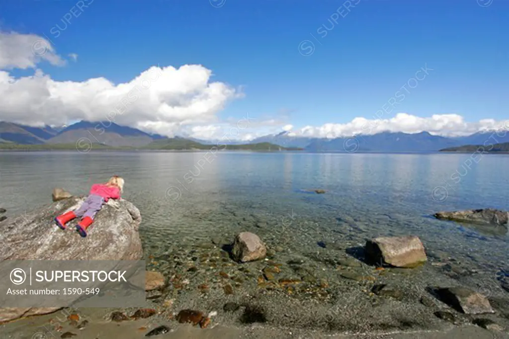 New Zealand, Lake Manapouri (Near Te Anau), Girl lying on stone