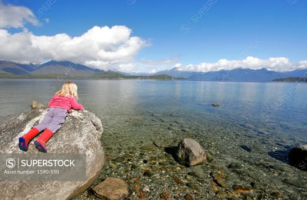 New Zealand, Lake Manapouri (Near Te Anau), Girl lying on stone
