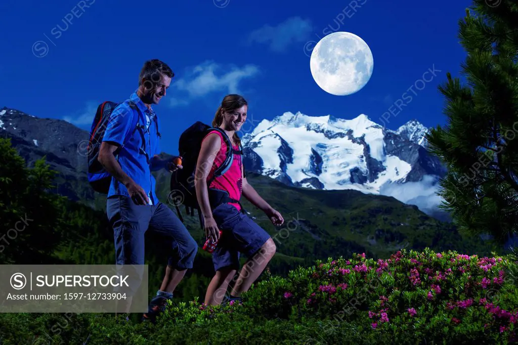 Group hiking at night with full moon near Gibidum in Valais