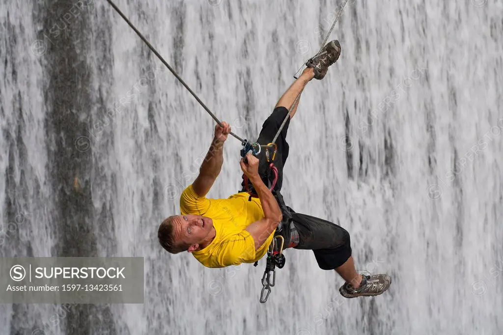 man climbing in a waterfall