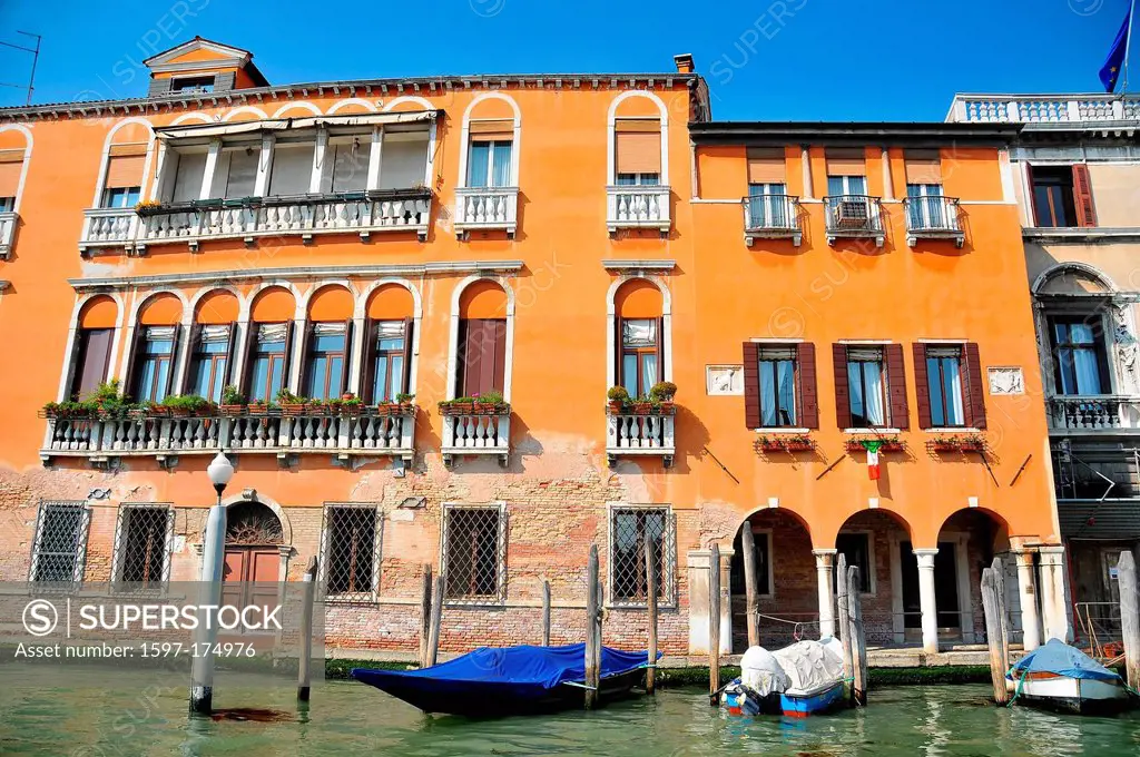 beautiful ocher traditional venetian palace on the grand canal, with gondola and small boat moored up, decorated with window boxes, and inserted ancie...