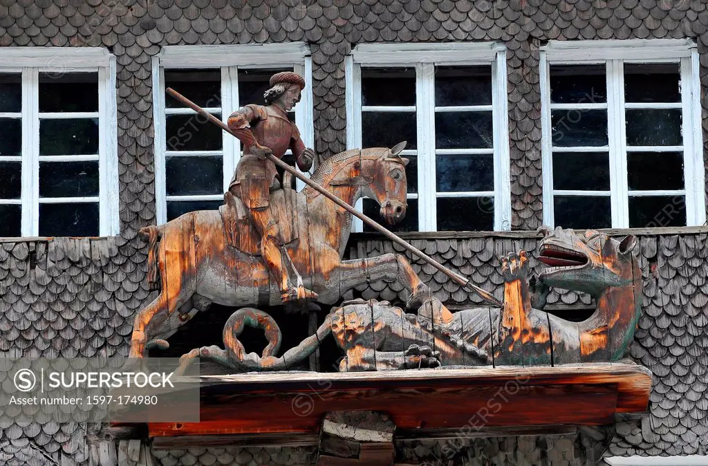 Old wooden statue high on a house of Saint George killing the dragon.