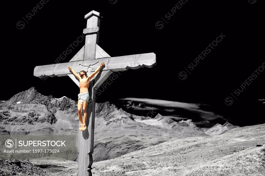 Stunning and dramatic enhanced monochrome cross with jesus christ crucified, in the mountains, above a lake, with high alps in the distance,