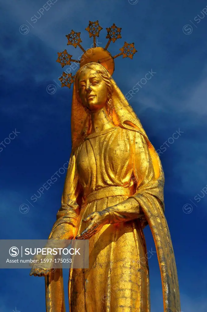 Beautiful Gold statue of the virgin Mary standing on the top of an ancient pass between Italy and Switzerland. the halo containing snowflakes, reflect...