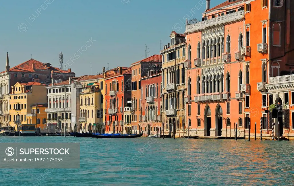 brightly painted houses and palaces line the waterfront of the grand canal in Venice, Italy. gondolas can be seen moored