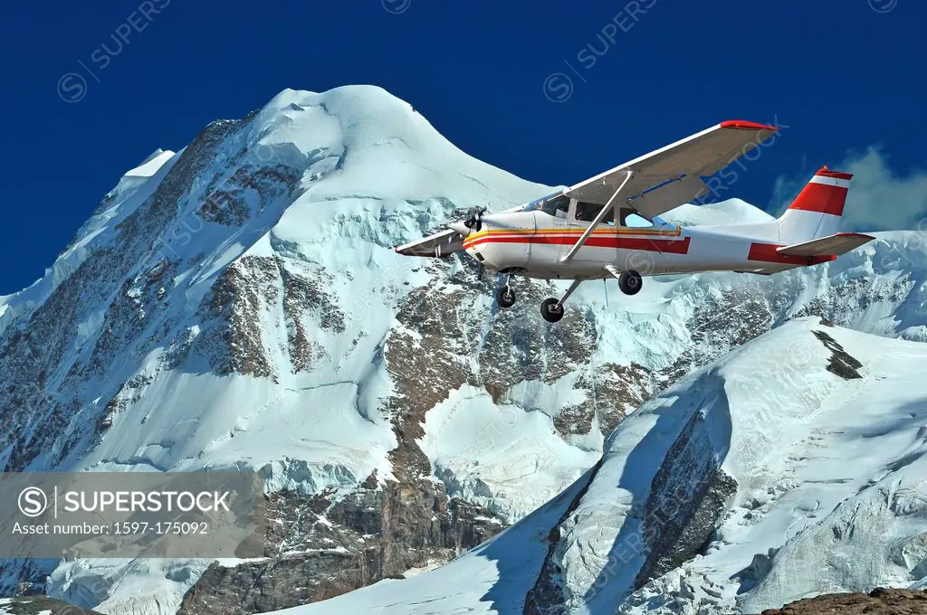 A light aircraft flies past the summit of an ice covered mountain giving a fantastic view