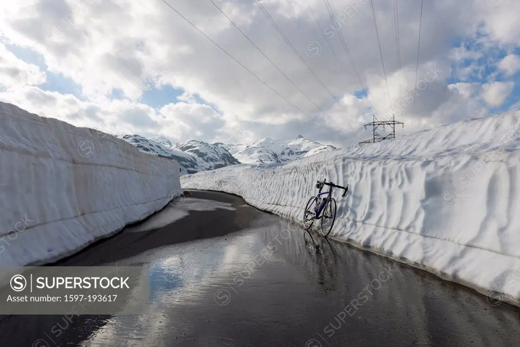 Bicycle leaning on a snow wall on the mountain pass san gottardo with snow-capped mountain in background in uri Switzerland, Europe,