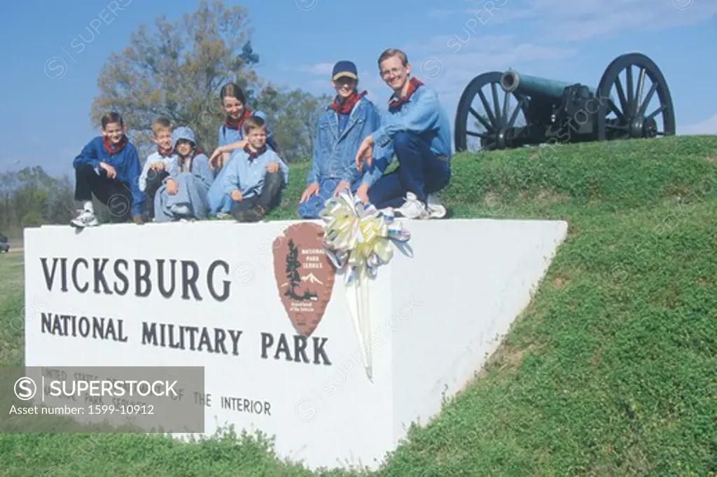 Family on sign on green grass at entrance of Vicksburg National Military Park, MS