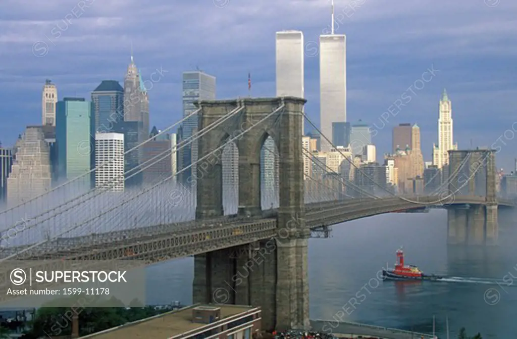 View of New York skyline, Brooklyn Bridge over the East River and tugboat in fog, NY