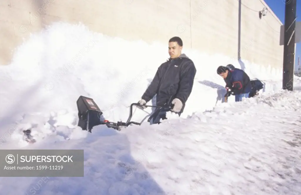 Man uses snow blower to clear snow from sidewalk in New Jersey near New York City after winter snowstorm