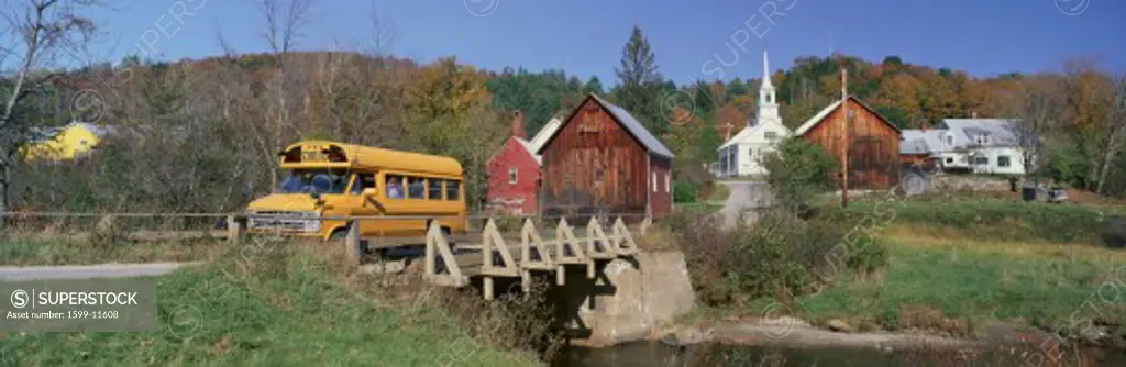 Yellow school bus crossing wooden bridge over Waits River in autumn, VT