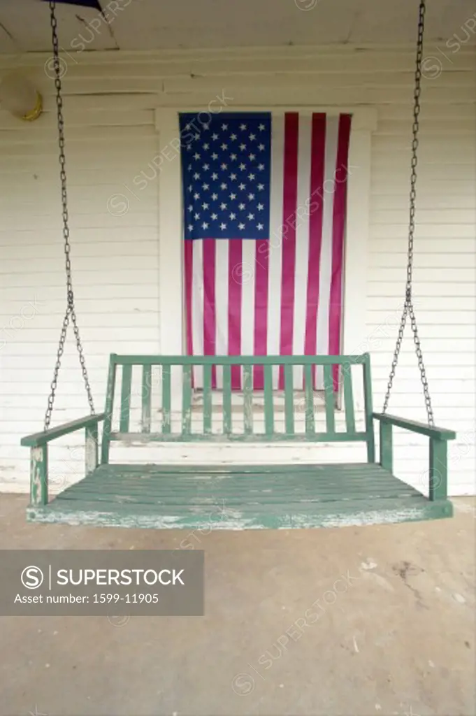 Old swing on porch displaying an American Flag and patriotic theme near Barstow CA off Route 59