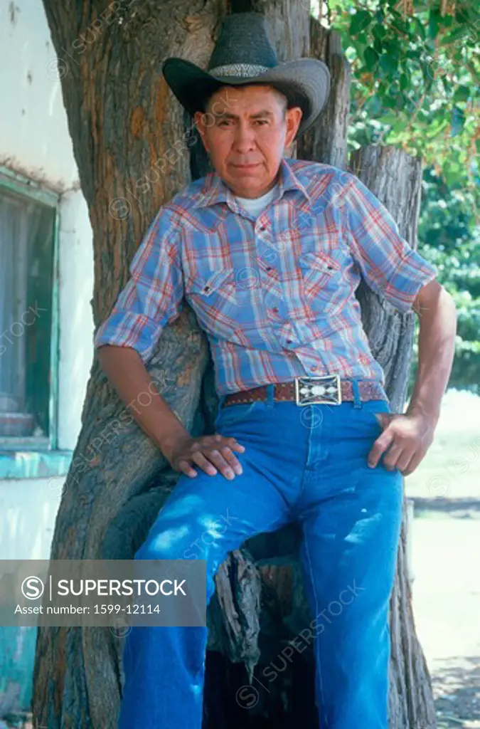 A Mexican-American cowboy leaning against a tree, AZ