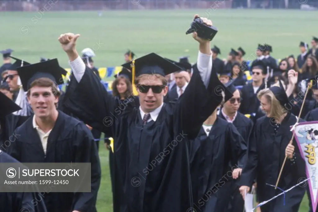 Graduates of the University of California, Los Angeles, CA, attend their graduation wearing red leis over their gowns. 1990. 