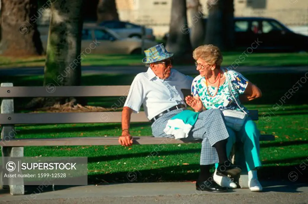 A senior couple sitting on a park bench talking, Santa Monica, CA