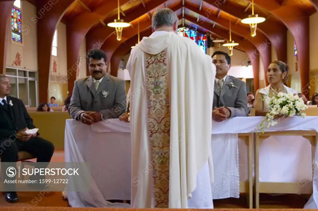 Catholic Priest administers wedding vows to two Latino-American couples at St. Thomas Catholic Church in Ojai, California