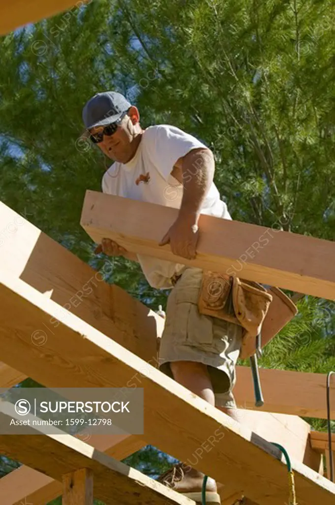 Carpenter lifts central beam of framing process in Southern California