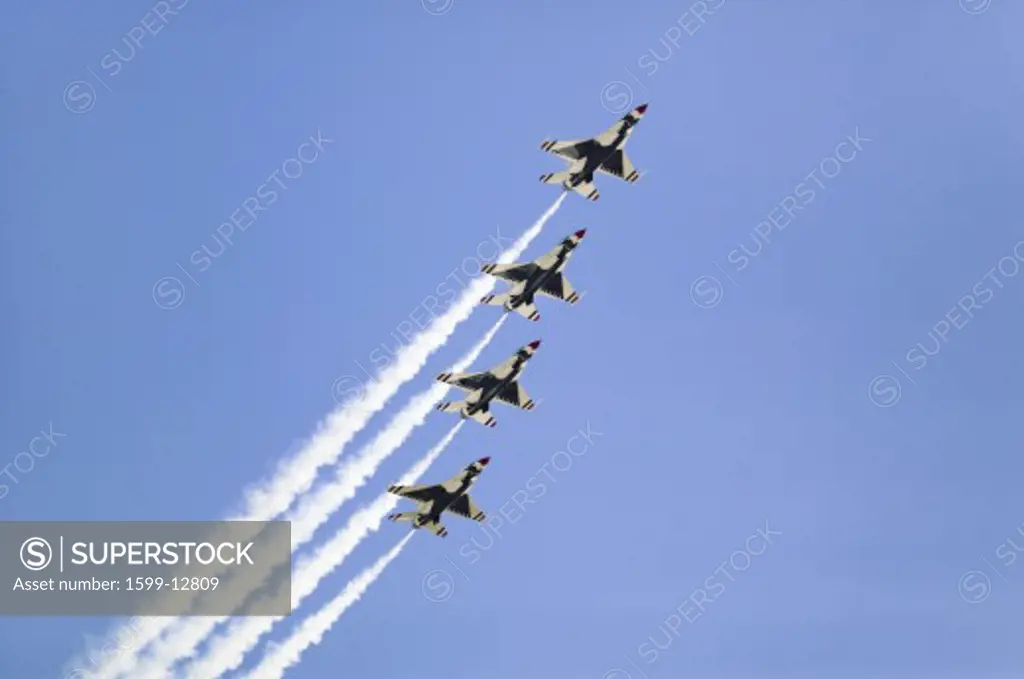 Four US Air Force F-16C Fighting Falcons, known as the Thunderbirds, flying in formation with white trailer of smoke over the 42nd Naval Base Ventura County (NBVC) Air Show at Point Mugu, Ventura County, Southern California.