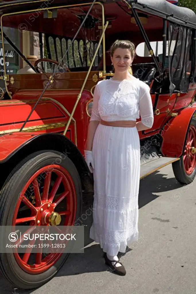 Woman in Victorian dress standing in front of antique car in Santa Paula, CA