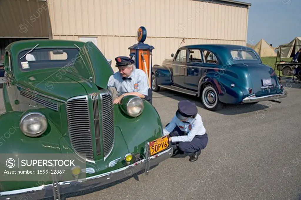Reenactment of two women gas attendants servicing 1940s car during World War II at Mid-Atlantic Air Museum World War II Weekend and Reenactment in Reading, PA held June 18, 2008