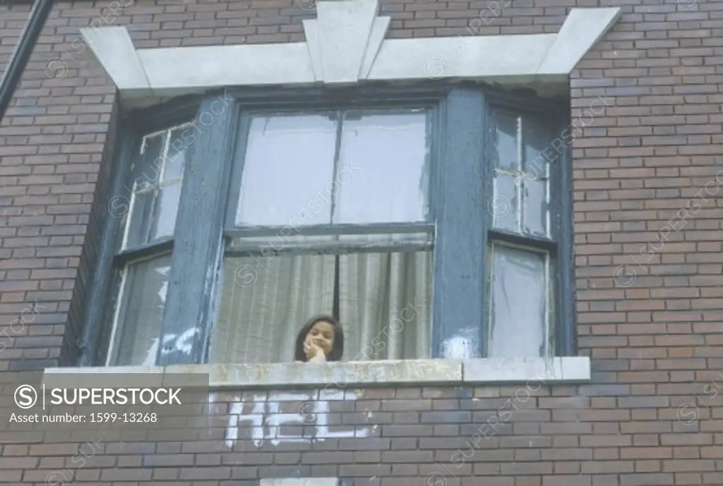 A child looking out of her apartment window, South Bronx, NY