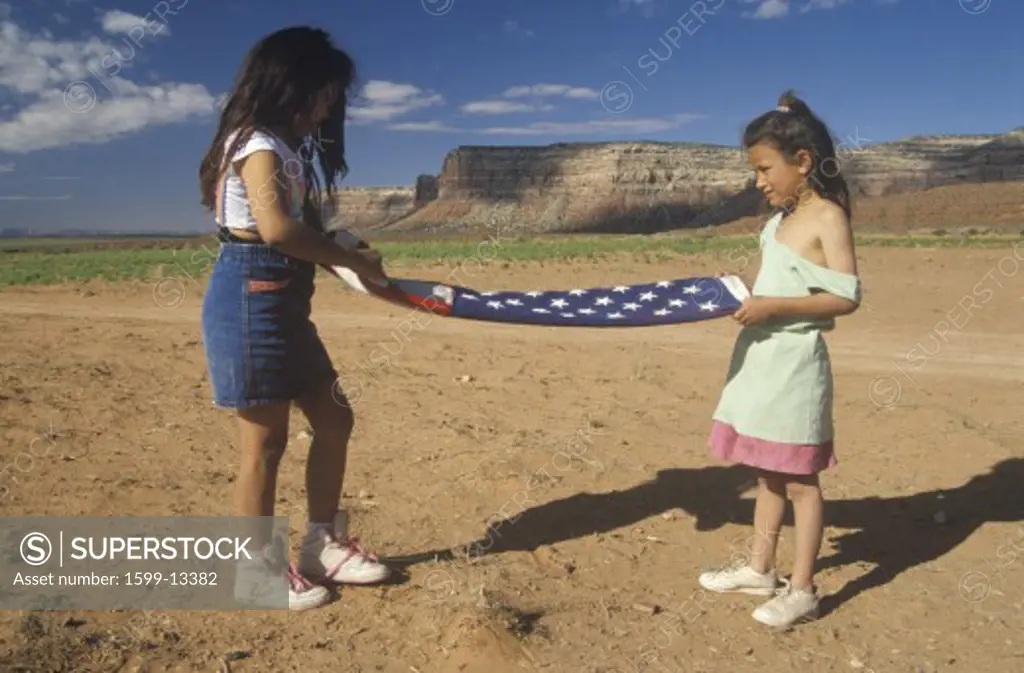 Two girls folding the American flag, Lee Ranch, southern UT
