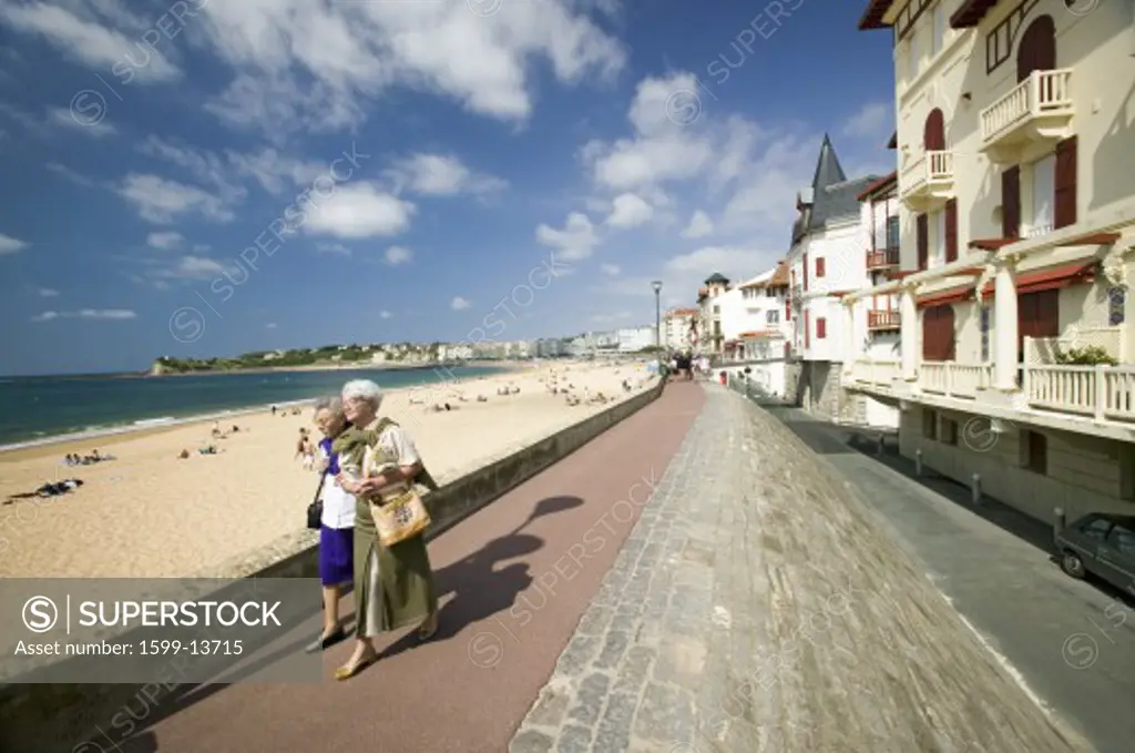 Two women walk down beach boardwalk at St. Jean de Luz, on the Cote Basque, South West France, a typical fishing village in the French-Basque region near the Spanish border
